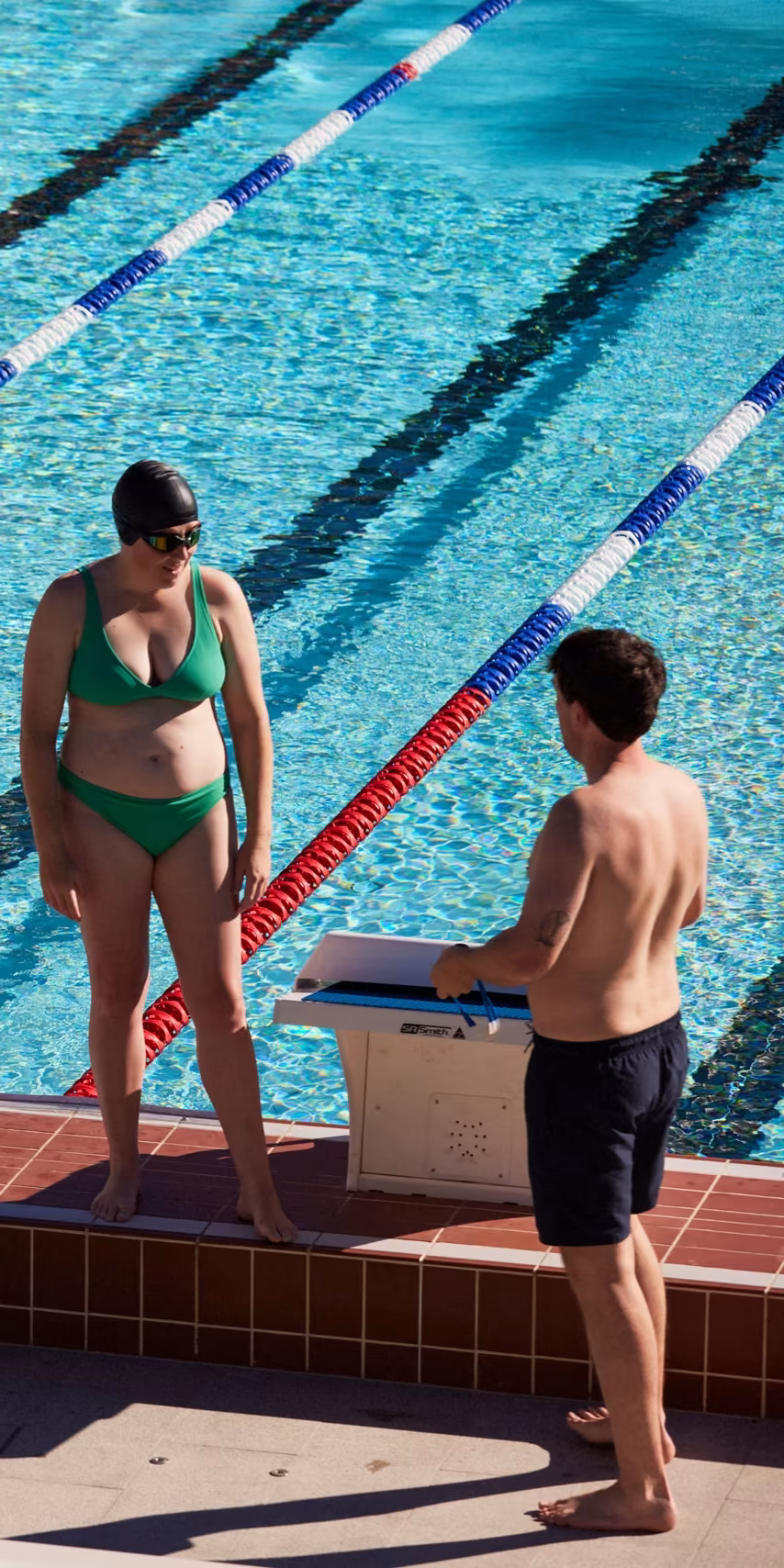 Two swimmers talking beside a starting block at the 50 metre outdoor pool