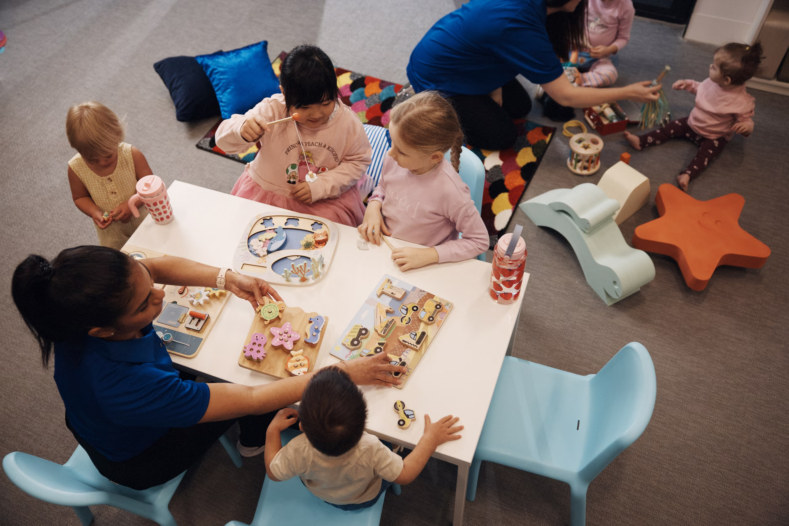 Children at the craft table with an educator in the crèche