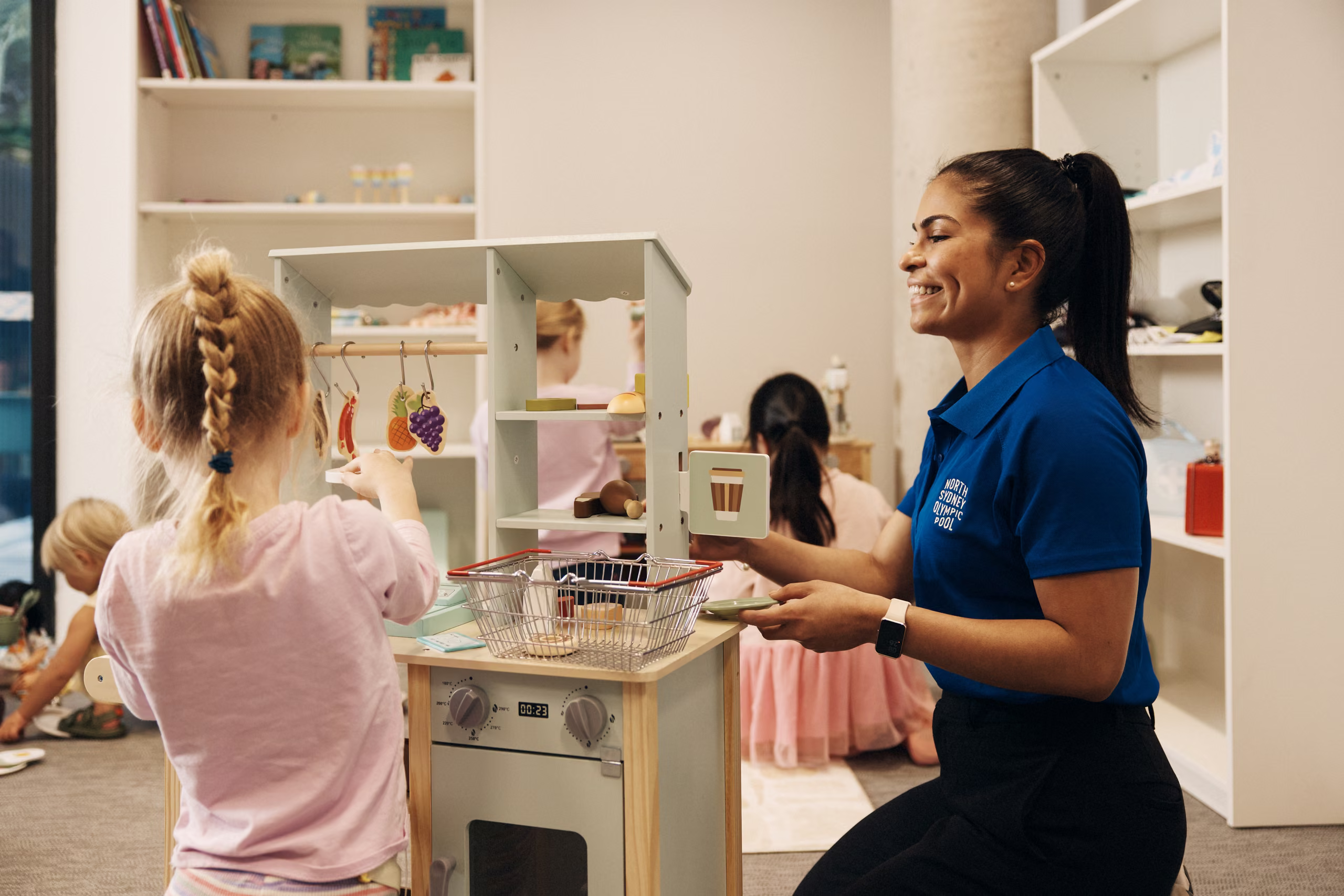 An educator playing with a child at the crèche play kitchen