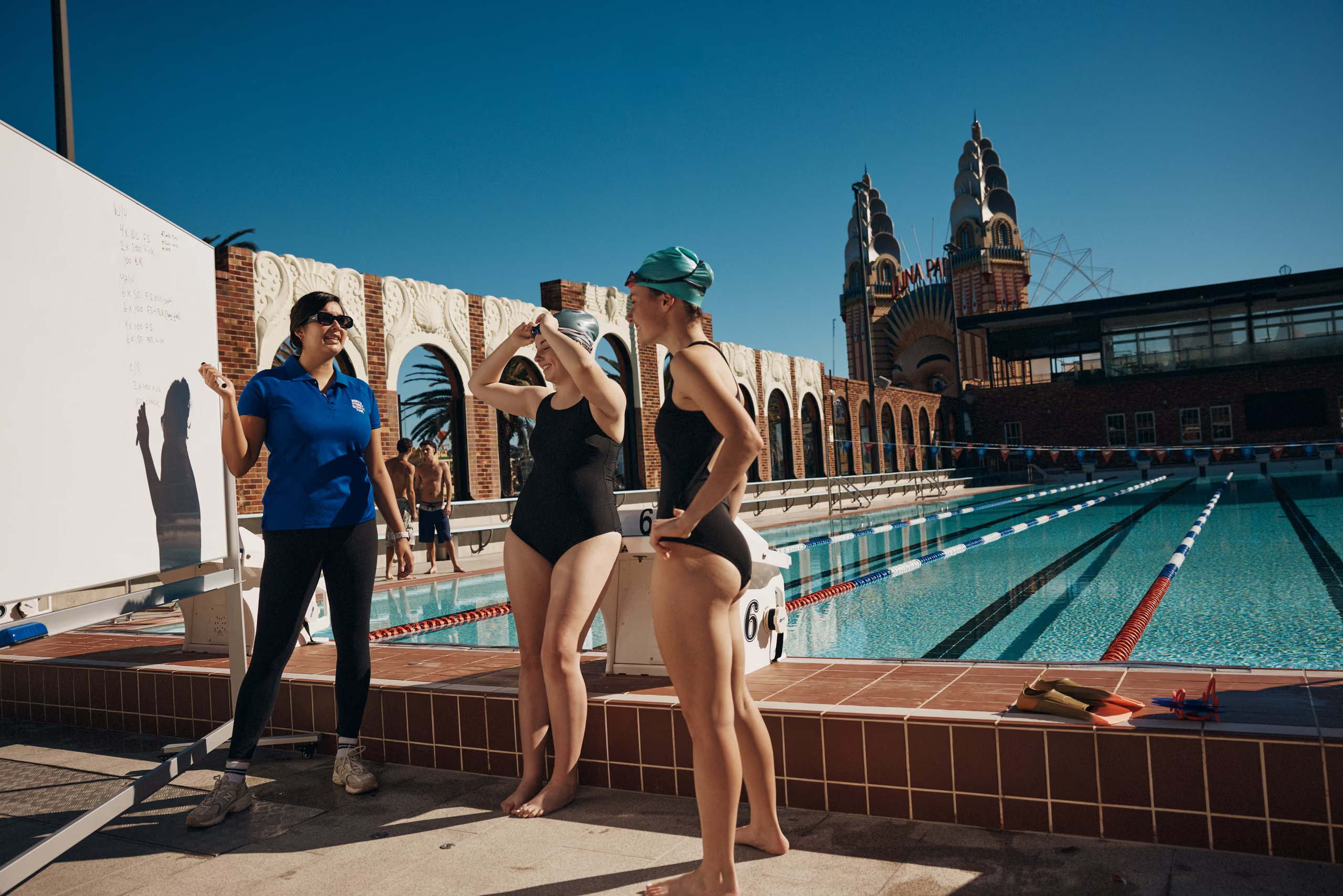 Swimmers in the outdoor 50 metre pool with the Sydney Harbour Bridge and city skyline behind
