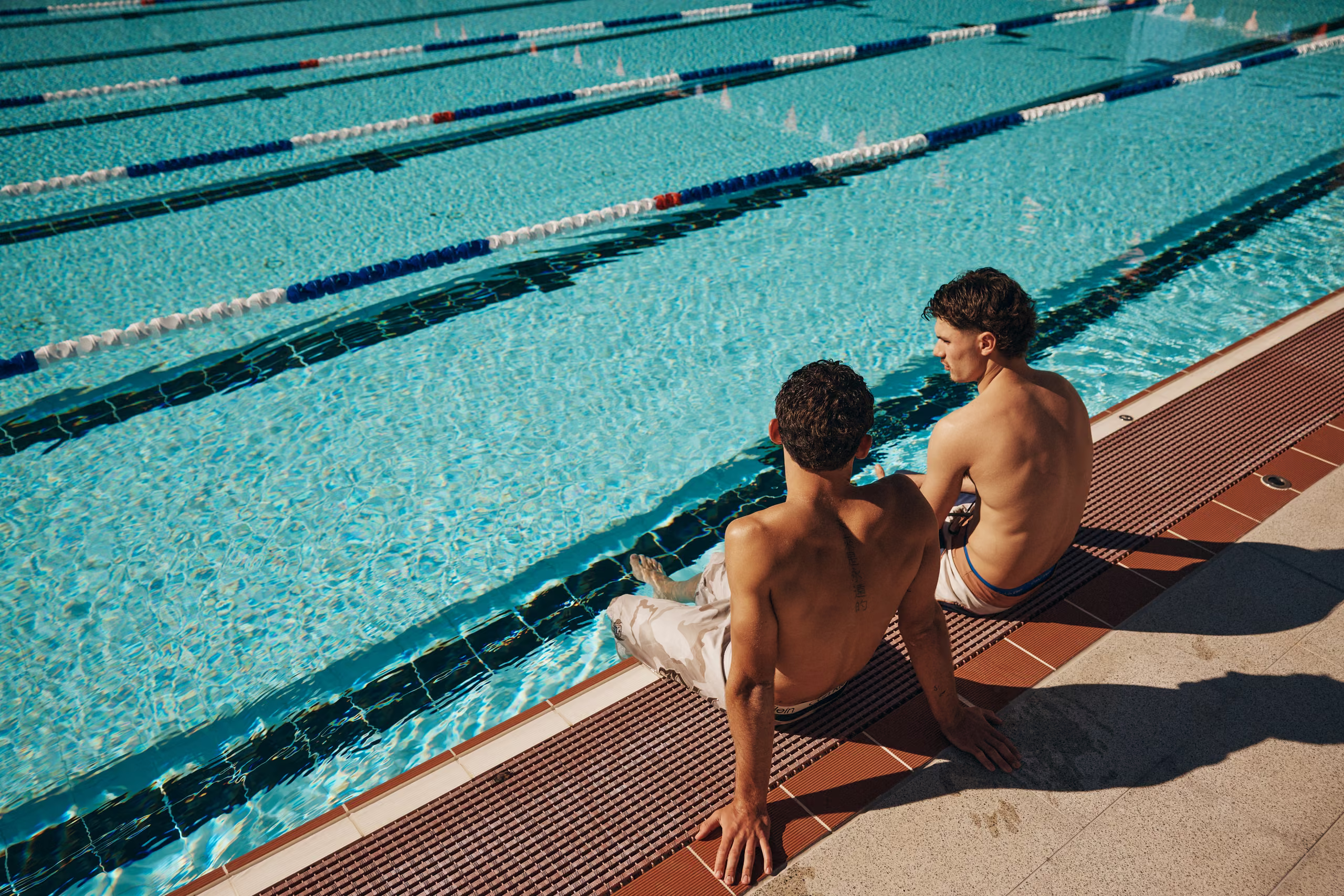 A swimmer in a lane with someone resting at the pool edge