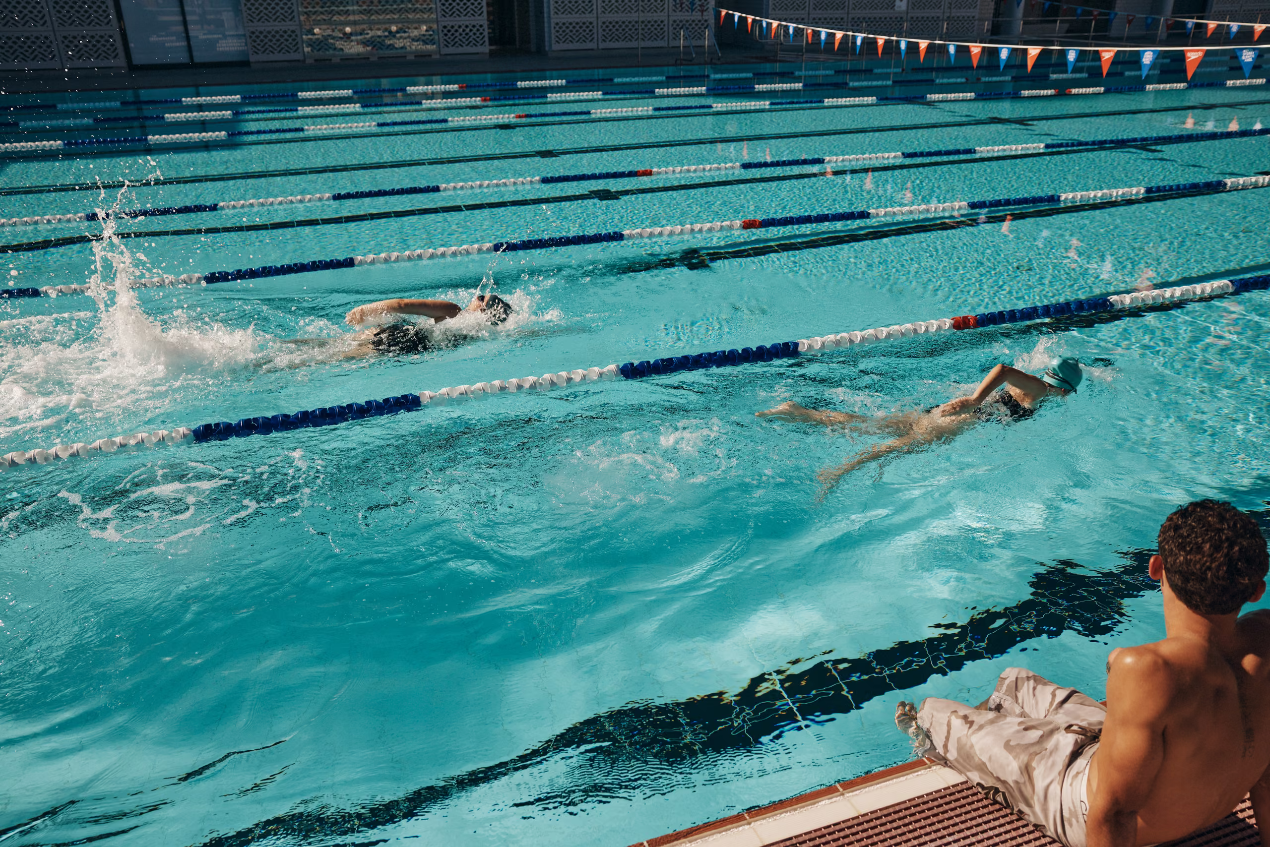 A swimmer mid freestyle stroke in a marked lane, water spraying from their arm