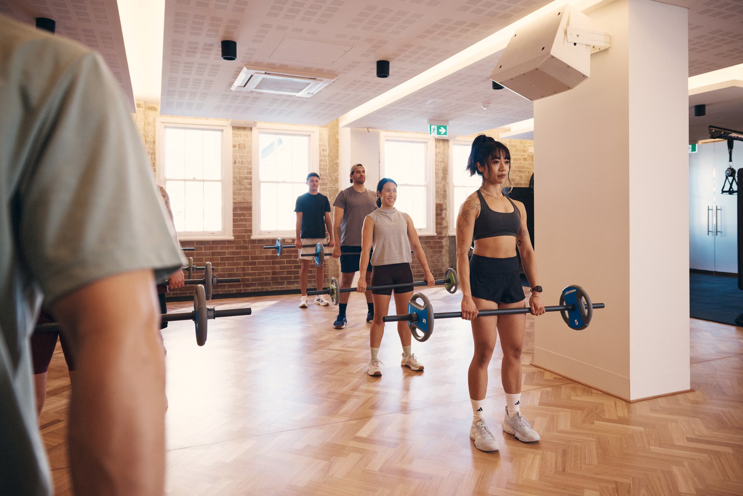 A group fitness class working with barbells in the studio
