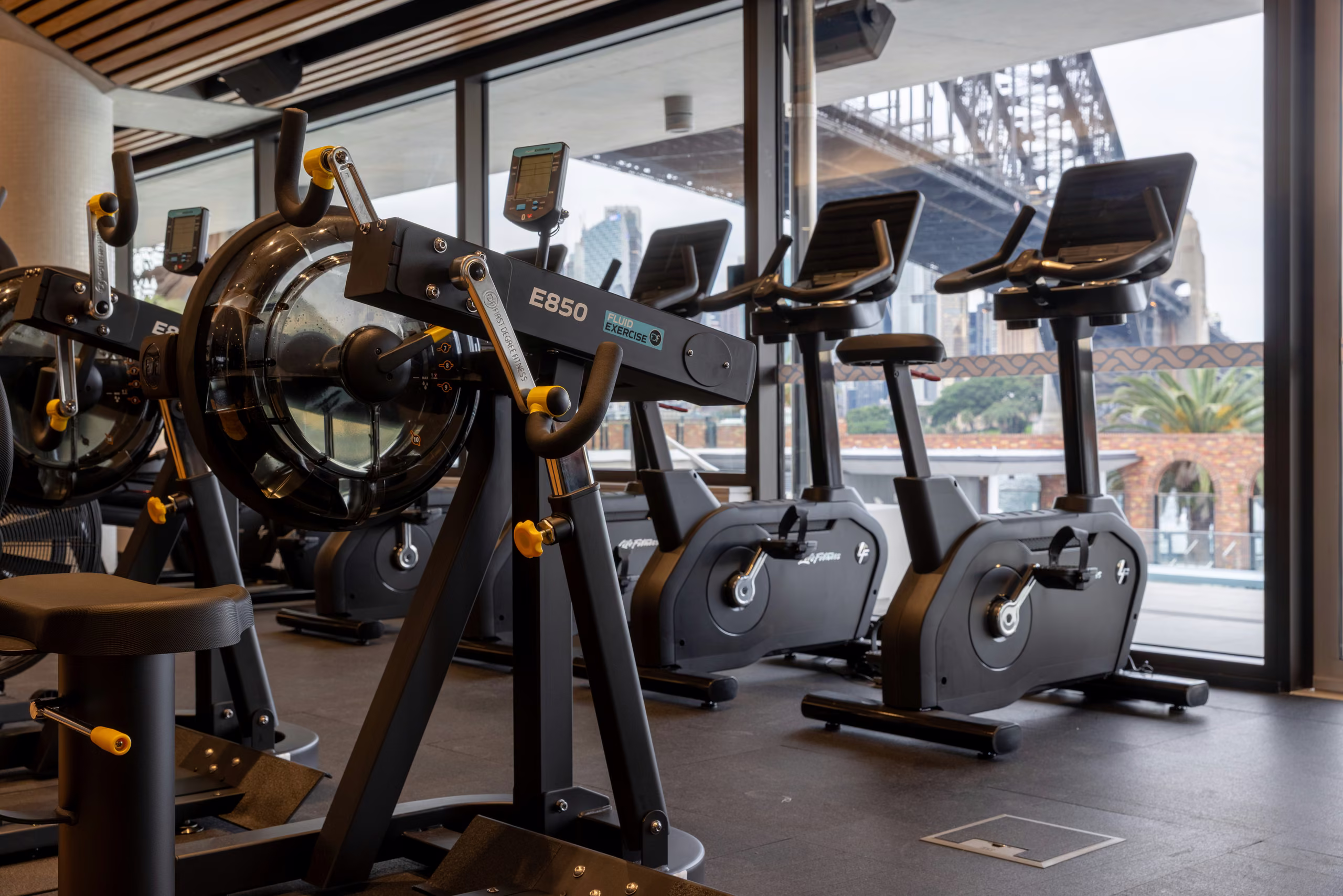 Cardio equipment on the gym floor with the Sydney Harbour Bridge through the window